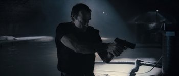 Movie still from “Chrysalis” (2007), directed by Julien Leclercq – A man holding a gun in a dark room; Medium shot, Low angle