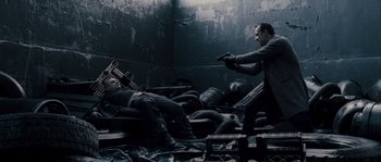 Movie still from “Chrysalis” (2007), directed by Julien Leclercq – A man in a suit and tie holding a gun in a room; Wide shot, High angle