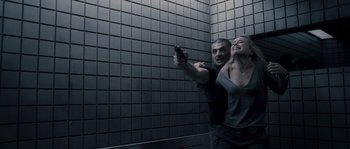 Movie still from “Chrysalis” (2007), directed by Julien Leclercq – A man and a woman holding a gun in a room; Medium shot, Over the shoulder angle
