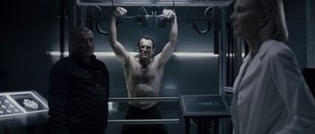 Movie still from “Chrysalis” (2007), directed by Julien Leclercq – A man with no shirt is lifting a bar; Medium shot, Low angle