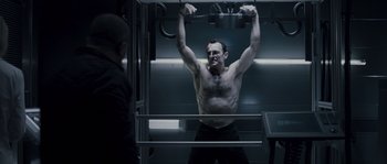 Movie still from “Chrysalis” (2007), directed by Julien Leclercq – A man with no shirt is standing in a gym; Medium shot, Low angle