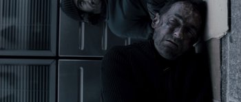 Movie still from “Chrysalis” (2007), directed by Julien Leclercq – A man in a black sweater and a man in a black hat; Close Up shot, Overhead angle