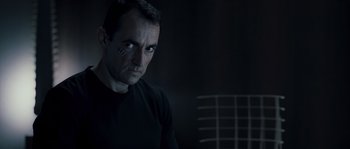 Movie still from “Chrysalis” (2007), directed by Julien Leclercq – A person wearing a black shirt; Close Up shot, Over the shoulder angle