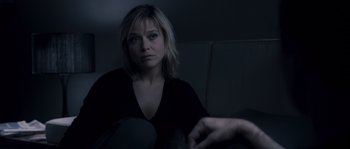Movie still from “Chrysalis” (2007), directed by Julien Leclercq – A woman sitting on a couch in a dark room; Close Up shot, Over the shoulder angle
