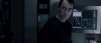 Movie still from “Chrysalis” (2007), directed by Julien Leclercq – A man in a black shirt is in front of a refrigerator; Close Up shot, Over the shoulder angle