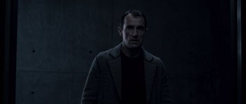 Movie still from “Chrysalis” (2007), directed by Julien Leclercq – A man wearing a jacket and a sweater; Medium shot, Low angle