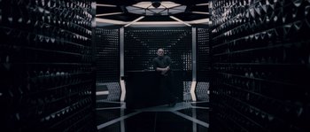 Movie still from “Chrysalis” (2007), directed by Julien Leclercq – A man sitting on a chair in front of a wall; Wide shot, Low angle