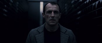 Movie still from “Chrysalis” (2007), directed by Julien Leclercq – A man in a black shirt and a gray jacket; Close Up shot, Low angle