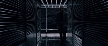 Movie still from “Chrysalis” (2007), directed by Julien Leclercq – A man standing in an elevator in a dark room; Wide shot, Low angle