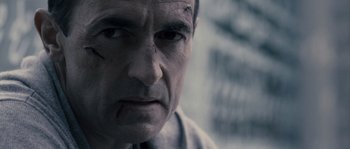 Movie still from “Chrysalis” (2007), directed by Julien Leclercq – A man's face in a black - and - white photo; Close Up shot, Over the shoulder angle