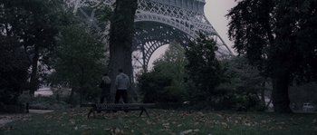 Movie still from “Chrysalis” (2007), directed by Julien Leclercq – Two people standing on a bench in front of the eiffel tower; Extreme Wide shot, Low angle