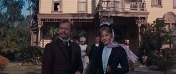 Movie still from “Cimarron” (1960), directed by Charles Walters – A man and a woman standing next to each other in front of a house; Medium shot, Low angle