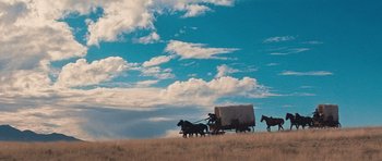 Movie still from “Cimarron” (1960), directed by Charles Walters – A group of horses pulling a wagon down a hill; Extreme Wide shot, Low angle