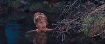 Movie still from “Cimarron” (1960), directed by Charles Walters – A woman in a body of water with a tree in the background; Close Up shot, High angle