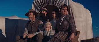 Movie still from “Cimarron” (1960), directed by Charles Walters – A group of people sitting on top of a wagon; Medium shot, Low angle