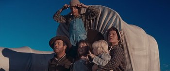Movie still from “Cimarron” (1960), directed by Charles Walters – A group of people standing next to each other in front of an object; Medium shot, Low angle