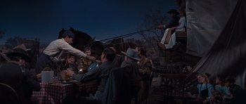 Movie still from “Cimarron” (1960), directed by Charles Walters – A group of people sitting around a table; Wide shot, High angle