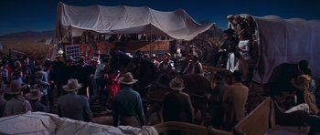 Movie still from “Cimarron” (1960), directed by Charles Walters – A group of men standing around a horse drawn carriage at night; Wide shot, High angle