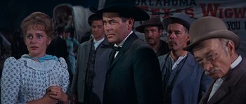 Movie still from “Cimarron” (1960), directed by Charles Walters – A group of men standing next to each other wearing hats; Medium shot, Low angle