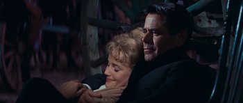 Movie still from “Cimarron” (1960), directed by Charles Walters – A man and a woman are hugging each other; Medium shot, Over the shoulder angle
