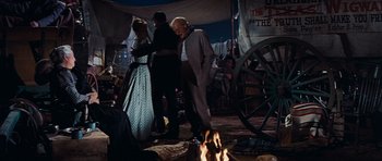 Movie still from “Cimarron” (1960), directed by Charles Walters – A man and a woman standing in front of a fire; Wide shot, Low angle
