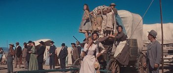 Movie still from “Cimarron” (1960), directed by Charles Walters – A group of people standing on top of a wagon; Wide shot, Low angle