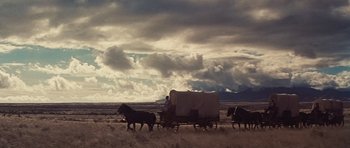 Movie still from “Cimarron” (1960), directed by Charles Walters – Two horses pulling a covered wagon down a dirt road; Extreme Wide shot, Low angle