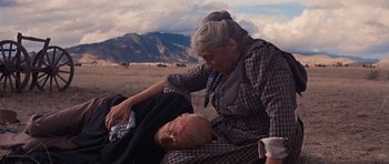 Movie still from “Cimarron” (1960), directed by Charles Walters – An older woman and a man laying on the ground in a field; Medium shot, Low angle