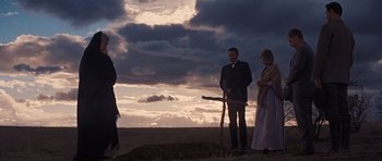 Movie still from “Cimarron” (1960), directed by Charles Walters – A group of people standing in a field with clouds in the background; Wide shot, Low angle