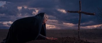 Movie still from “Cimarron” (1960), directed by Charles Walters – An older woman laying on the ground in a field; Wide shot, Low angle