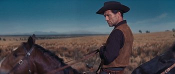Movie still from “Cimarron” (1960), directed by Charles Walters – A man riding a horse in the middle of a field; Medium shot, Low angle