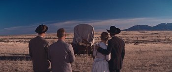 Movie still from “Cimarron” (1960), directed by Charles Walters – A group of people standing around a covered wagon; Wide shot, Low angle