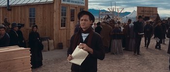 Movie still from “Cimarron” (1960), directed by Charles Walters – A man holding a book while standing in front of a crowd of people; Medium shot, Low angle