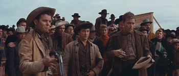 Movie still from “Cimarron” (1960), directed by Charles Walters – A group of men in a crowd of people; Medium shot, Low angle