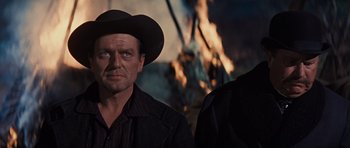 Movie still from “Cimarron” (1960), directed by Charles Walters – A man wearing a cowboy hat standing next to another man; Close Up shot, Over the shoulder angle