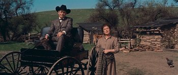 Movie still from “Cimarron” (1960), directed by Charles Walters – A man and a woman sitting in a horse - drawn carriage; Wide shot, Low angle