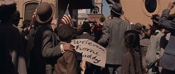 Movie still from “Cimarron” (1960), directed by Charles Walters – A group of people holding a sign that says " welcome home daddy "; Wide shot, High angle