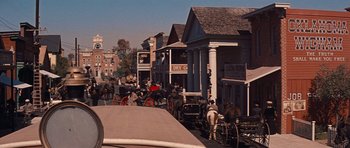 Movie still from “Cimarron” (1960), directed by Charles Walters – A group of people on a city street with horse drawn carriages; Extreme Wide shot, High angle