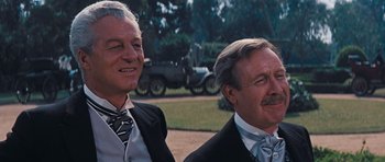 Movie still from “Cimarron” (1960), directed by Charles Walters – Two men in suits are standing next to each other outside; Close Up shot, Low angle