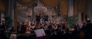 Movie still from “Cimarron” (1960), directed by Charles Walters – A large group of people sitting in front of chandeliers; Extreme Wide shot, High angle