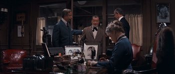 Movie still from “Cimarron” (1960), directed by Charles Walters – A group of people standing around a table; Medium shot, Over the shoulder angle