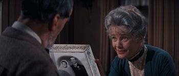 Movie still from “Cimarron” (1960), directed by Charles Walters – An older woman looking at an older man's picture; Close Up shot, Over the shoulder angle