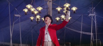 Movie still from “Circus World” (1964), directed by Henry Hathaway – A man wearing a red jacket and a black top hat; Medium shot, Low angle
