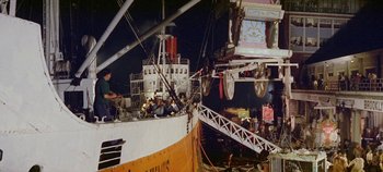 Movie still from “Circus World” (1964), directed by Henry Hathaway – A boat is docked at a pier with people sitting on it; Extreme Wide shot, High angle