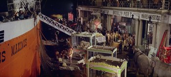 Movie still from “Circus World” (1964), directed by Henry Hathaway – A group of people standing next to a building; Extreme Wide shot, High angle