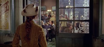 Movie still from “Circus World” (1964), directed by Henry Hathaway – A group of people sitting at a table in a restaurant; Wide shot, Over the shoulder angle