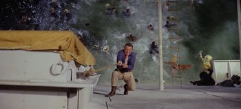 Movie still from “Circus World” (1964), directed by Henry Hathaway – A man in blue shirt and brown pants swinging a baseball bat; Wide shot, Overhead angle
