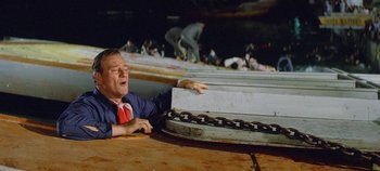 Movie still from “Circus World” (1964), directed by Henry Hathaway – A man in a suit and tie holding onto a chain; Medium shot, Overhead angle
