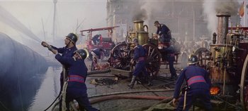 Movie still from “Circus World” (1964), directed by Henry Hathaway – A group of firemen are working on a fire hydrant; Wide shot, High angle