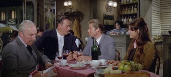 Movie still from “Circus World” (1964), directed by Henry Hathaway – A couple of men sitting at a table with wine glasses; Medium shot, Over the shoulder angle